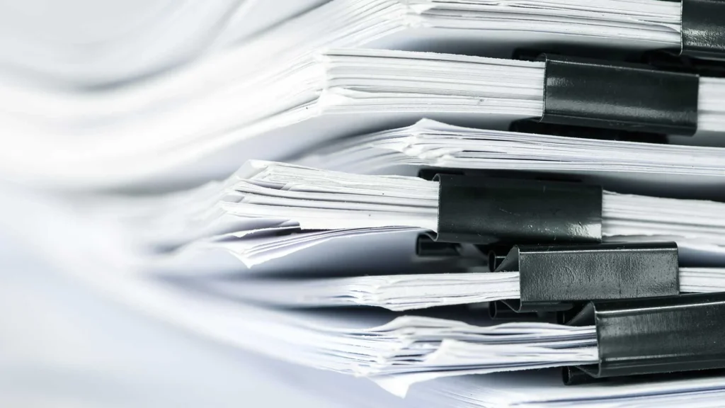 Stacks of white paper, clipped together.