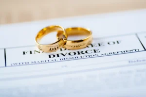 A divorce decree with two gold wedding rings on top.