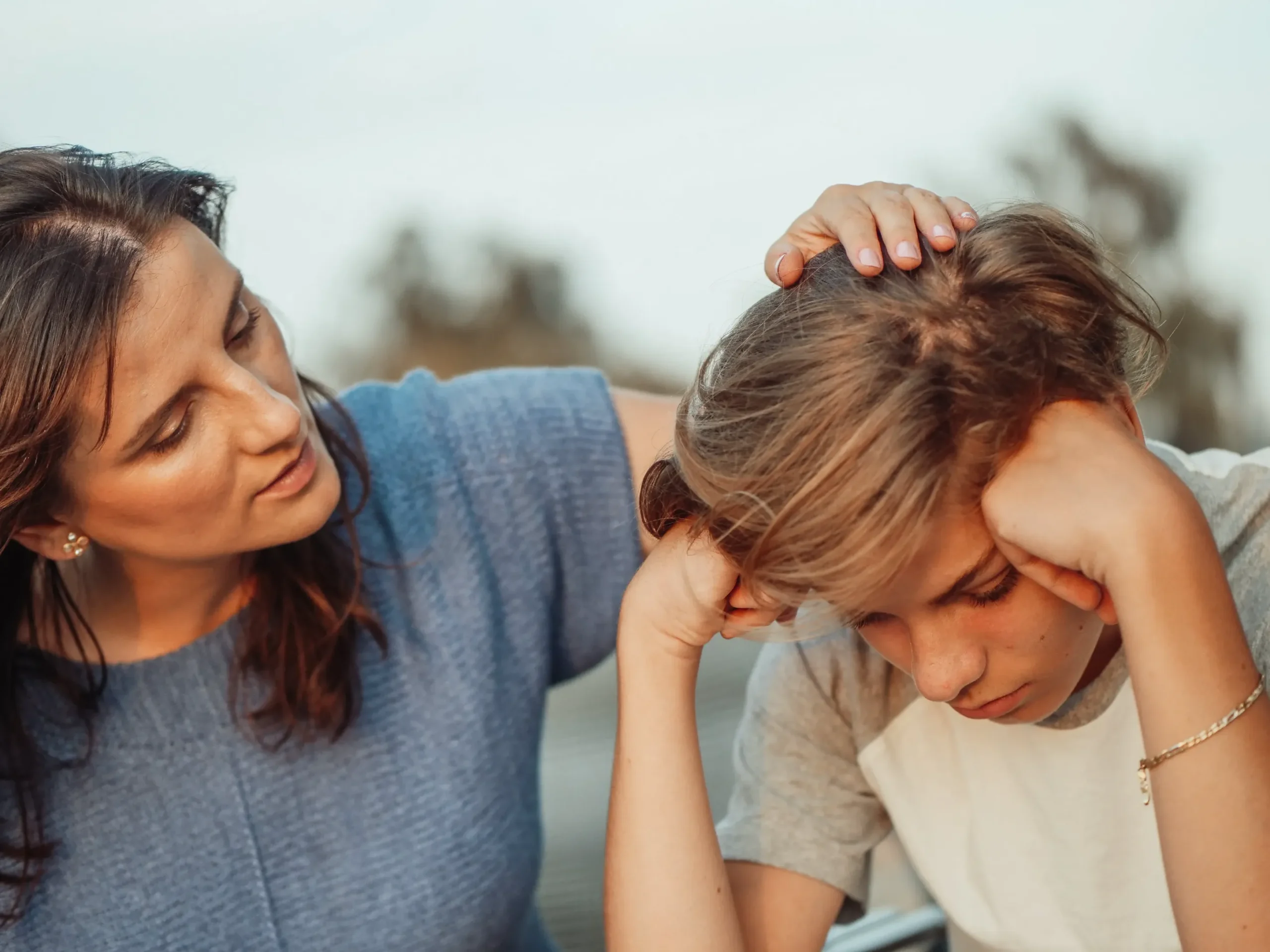 A mother strokes a young boy's head.