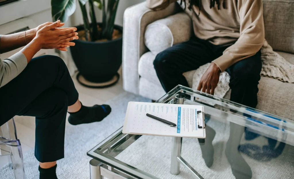 Two people sitting in a living room with papers on a coffee table.