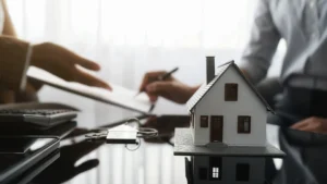 A client signing paperwork at a lawyers office, with a model house on the table.