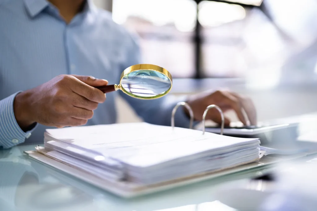 An attorney using a magnifying glass to read text in a binder.