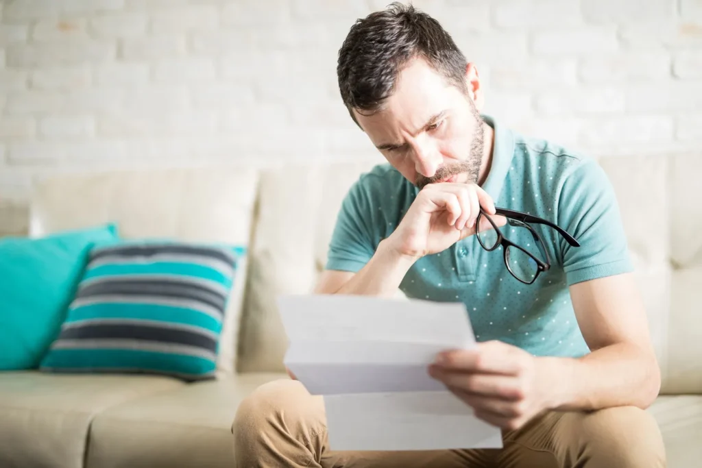 Man holding eye glasses while reading a document.