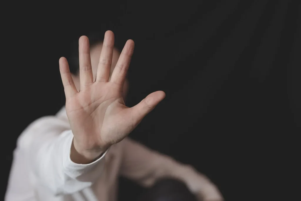 Person holding up their hand covering their face.