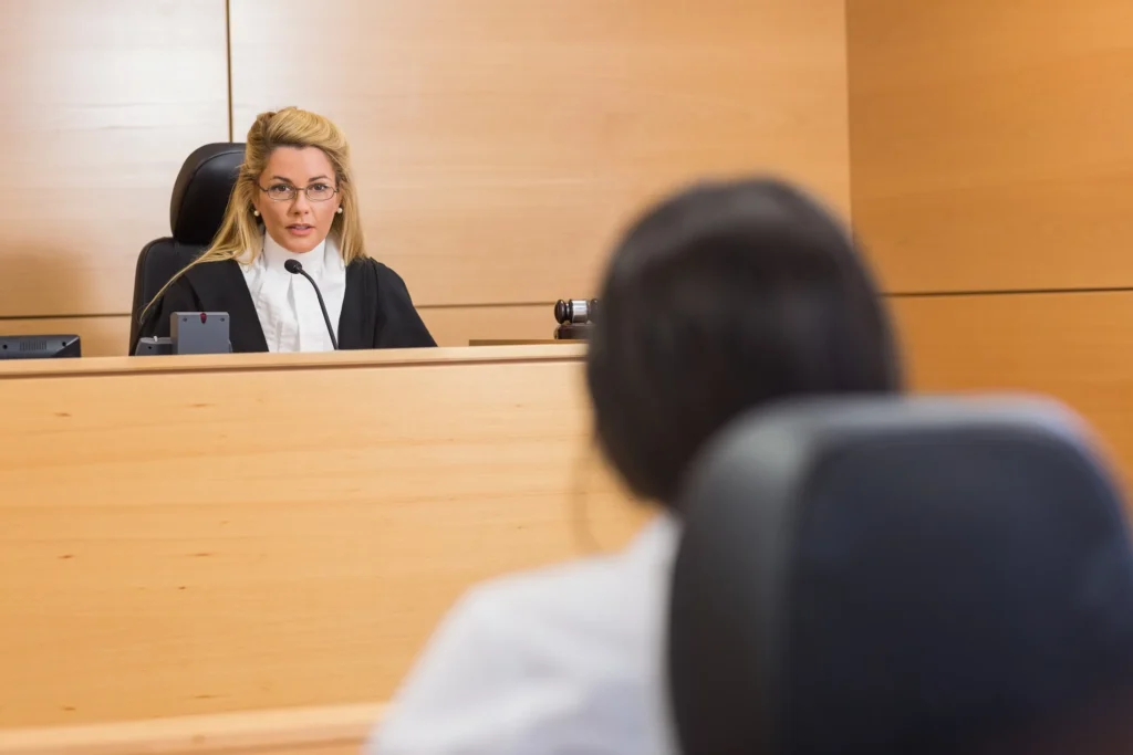 Person sitting in a courtroom in front of a judge.