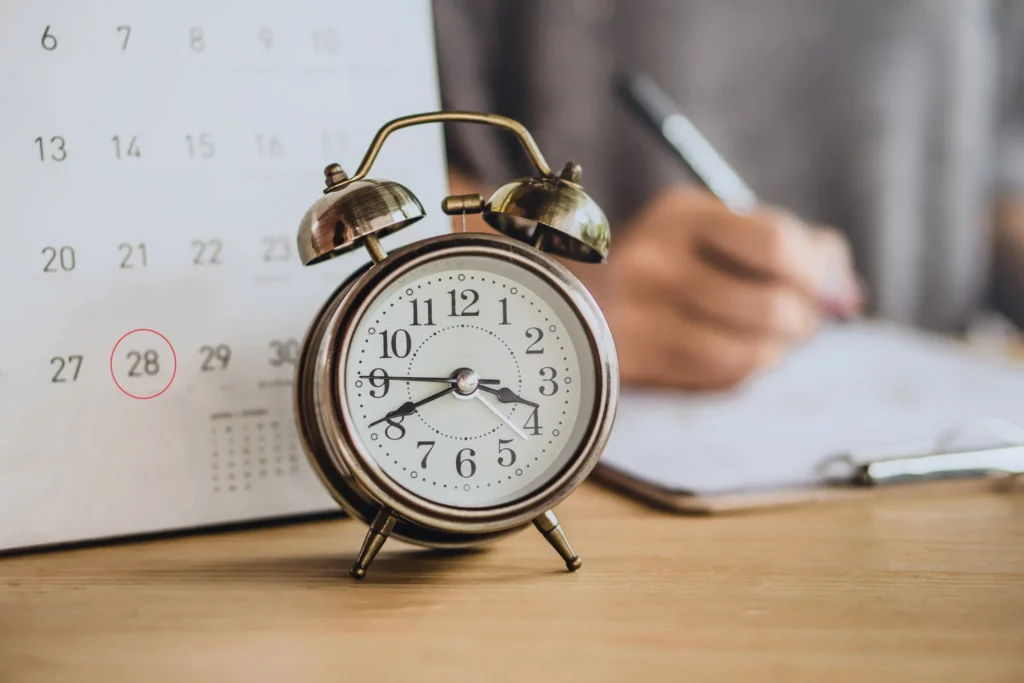 A calendar and a clock set on a table.
