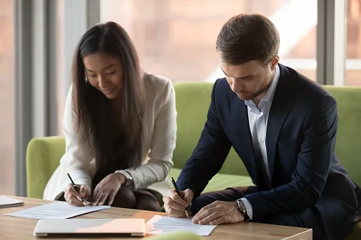 A man and woman signing papers.